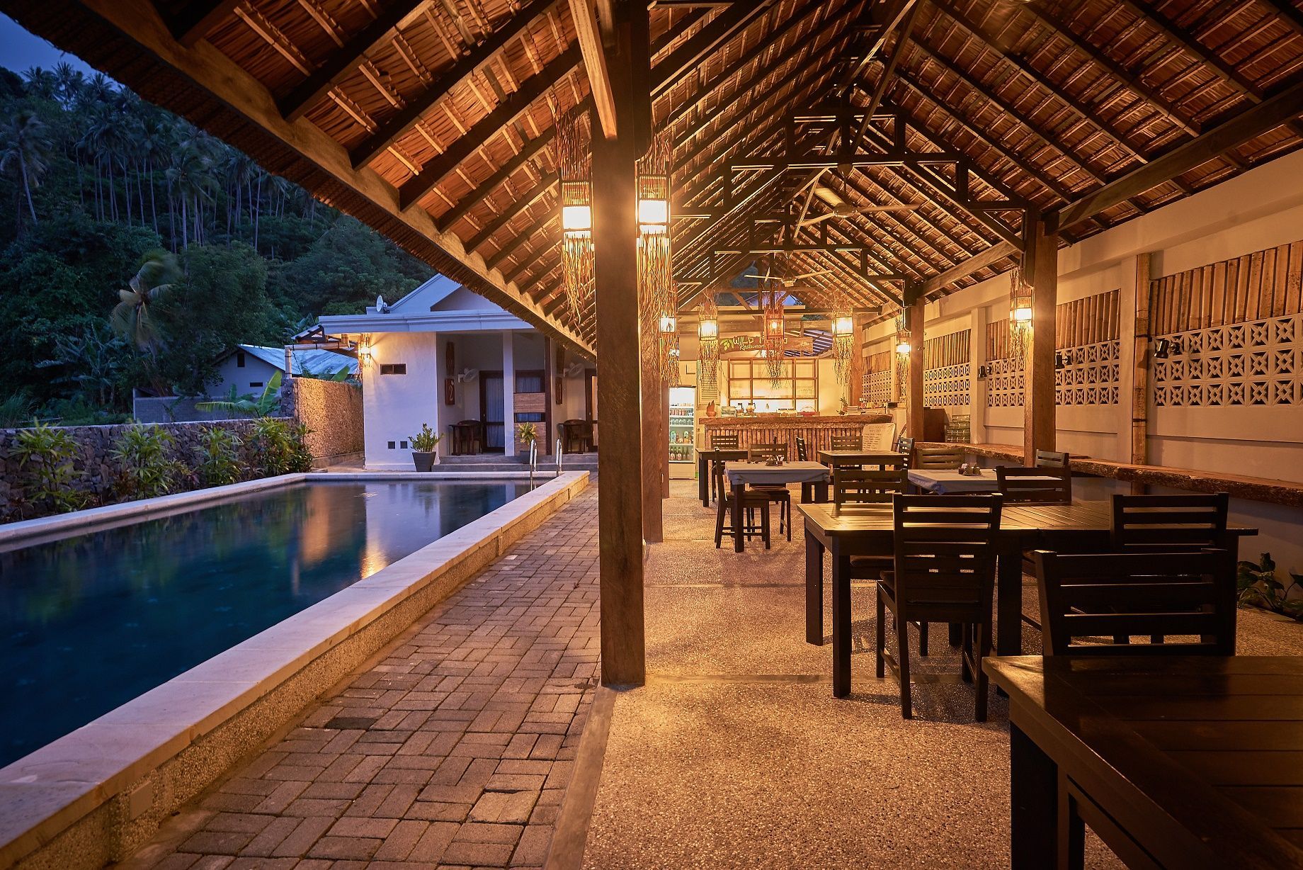 A restaurant with tables and chairs next to a swimming pool.