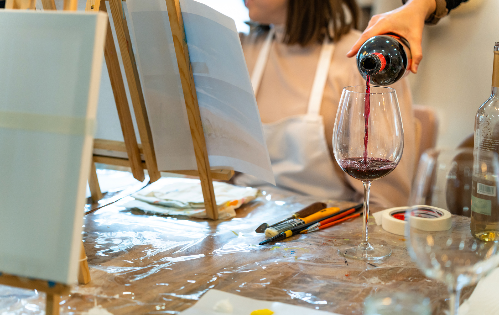 A woman is pouring wine into a glass on a table.