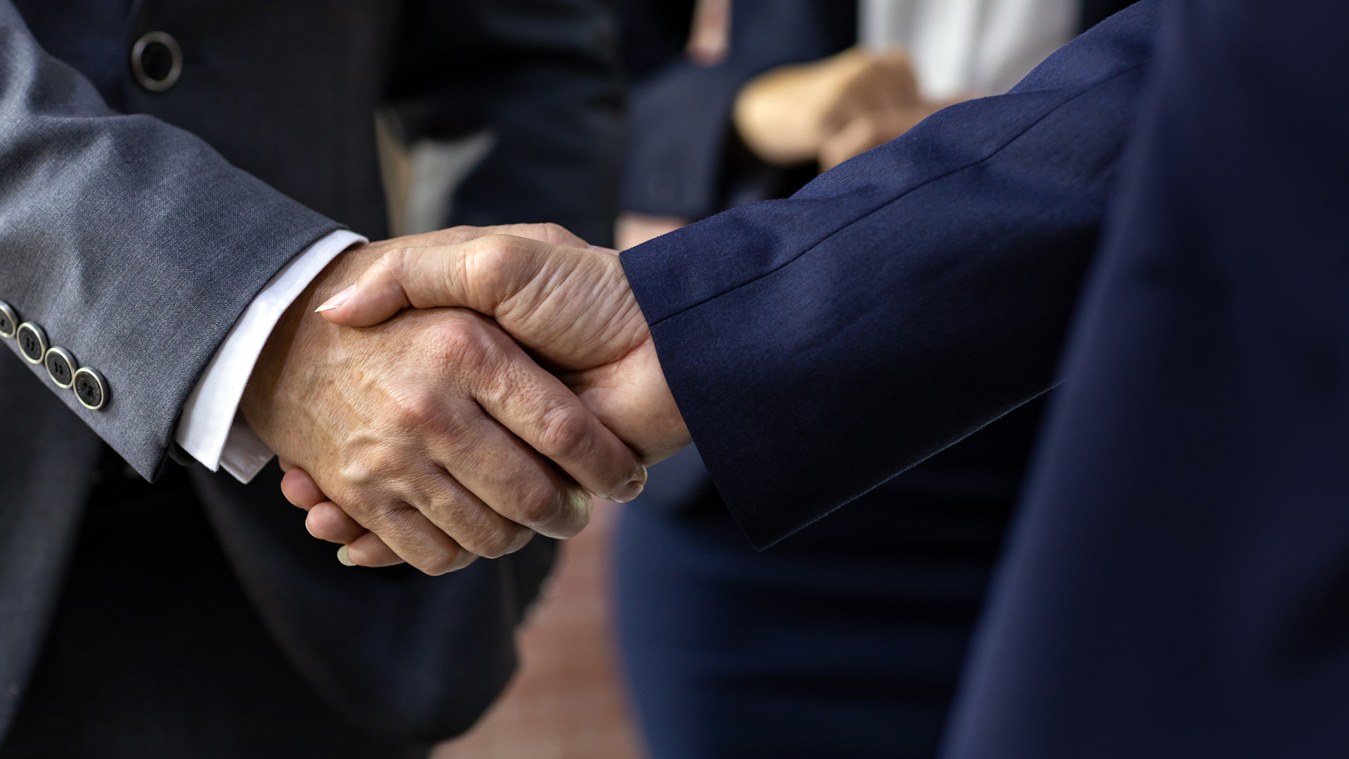 A man in a suit is shaking hands with another man in a suit.