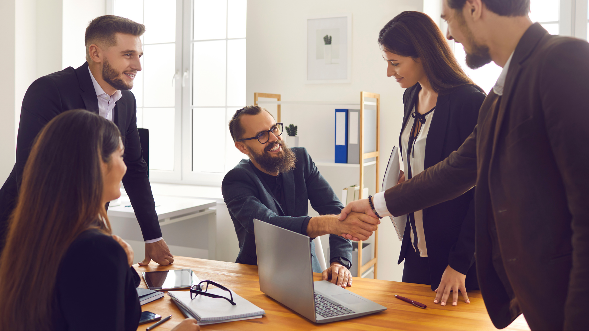 A group of business people are shaking hands in an office.