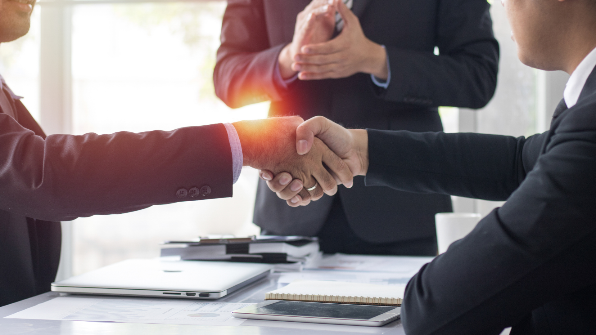 A group of business people are shaking hands over a table.