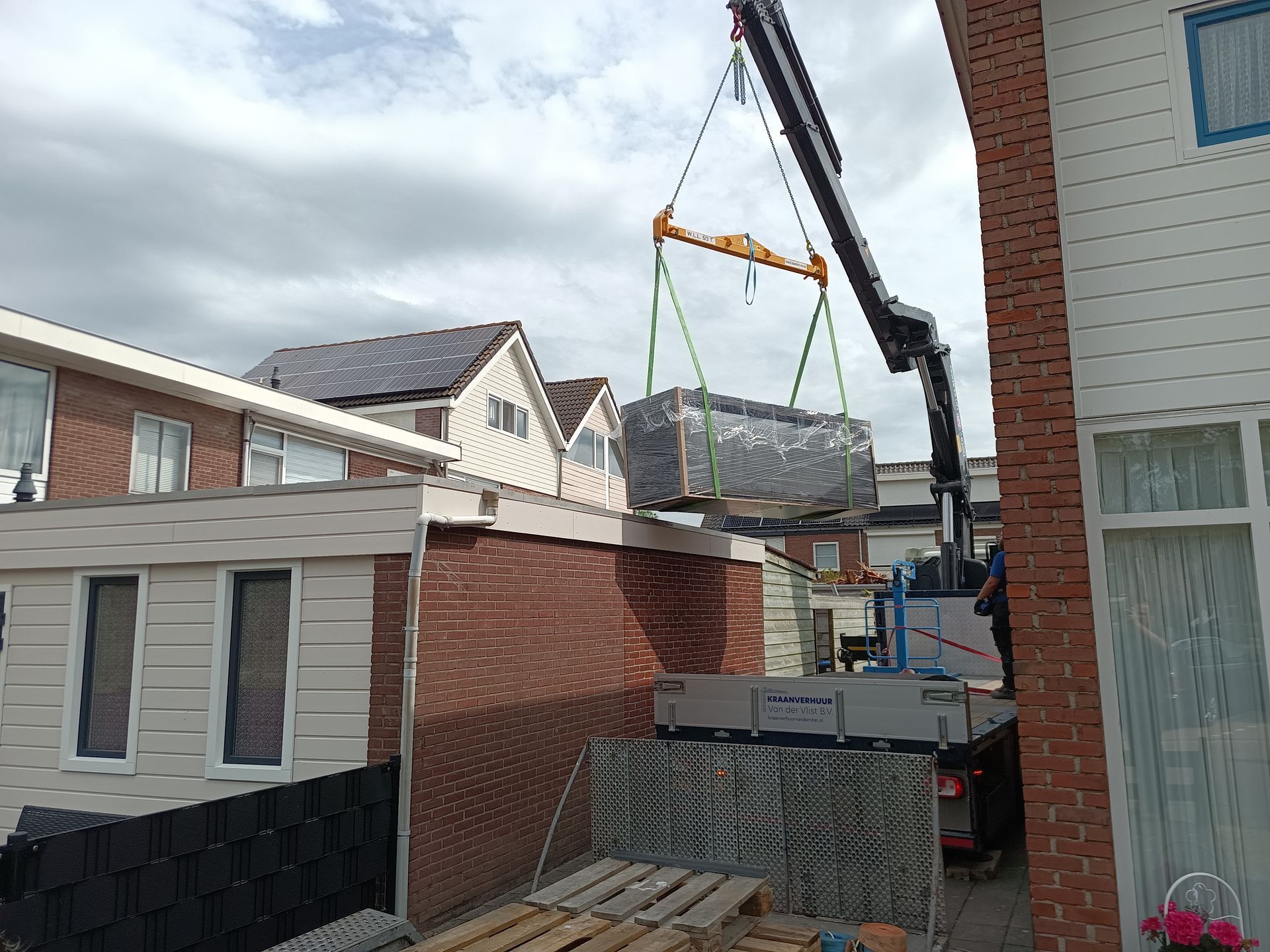 Een kraan hijst een grootaquarium over een dak.