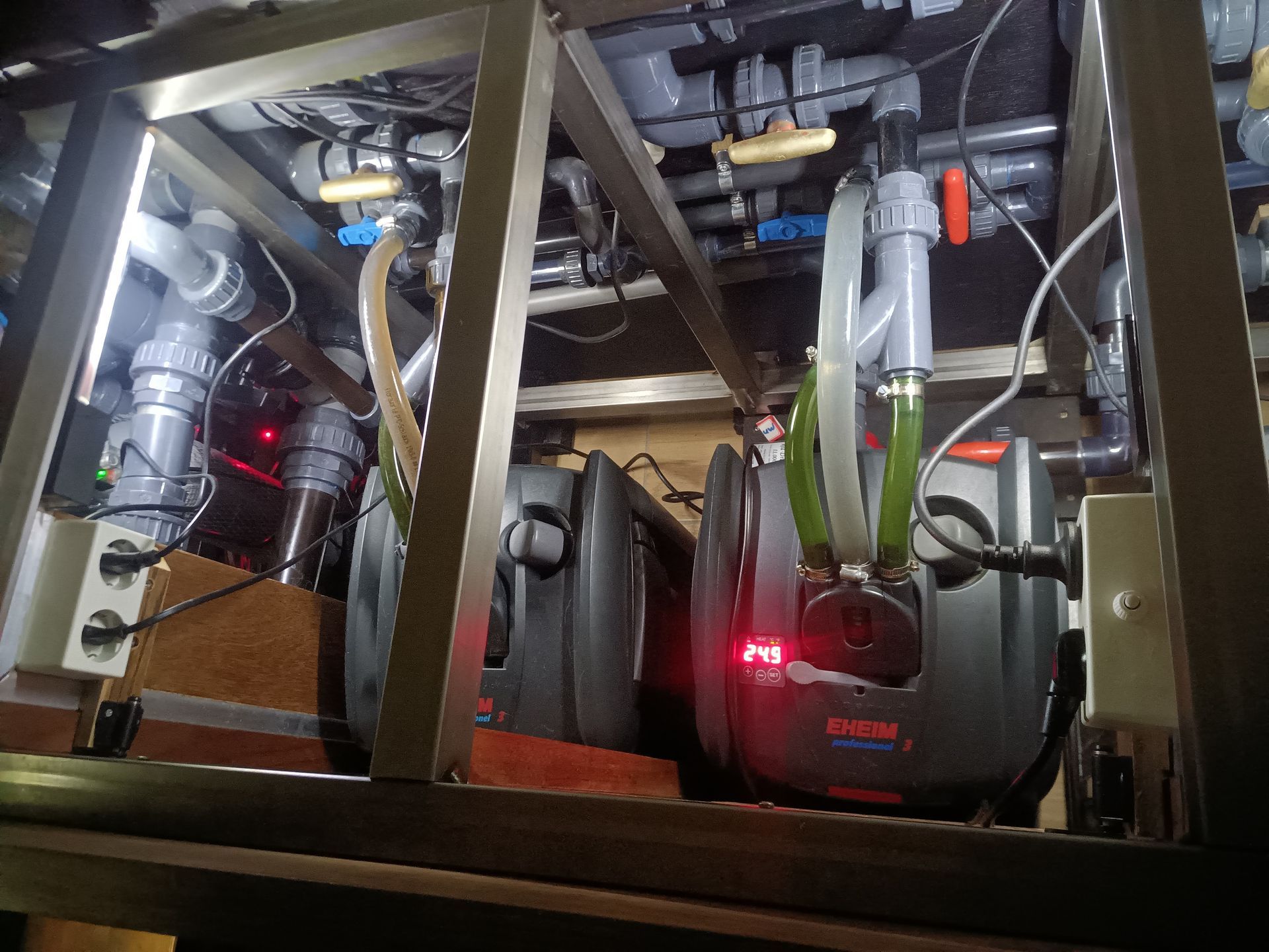 Aquariumfiltersysteem met grijze busfilters, PVC-buizen en elektrische componenten.