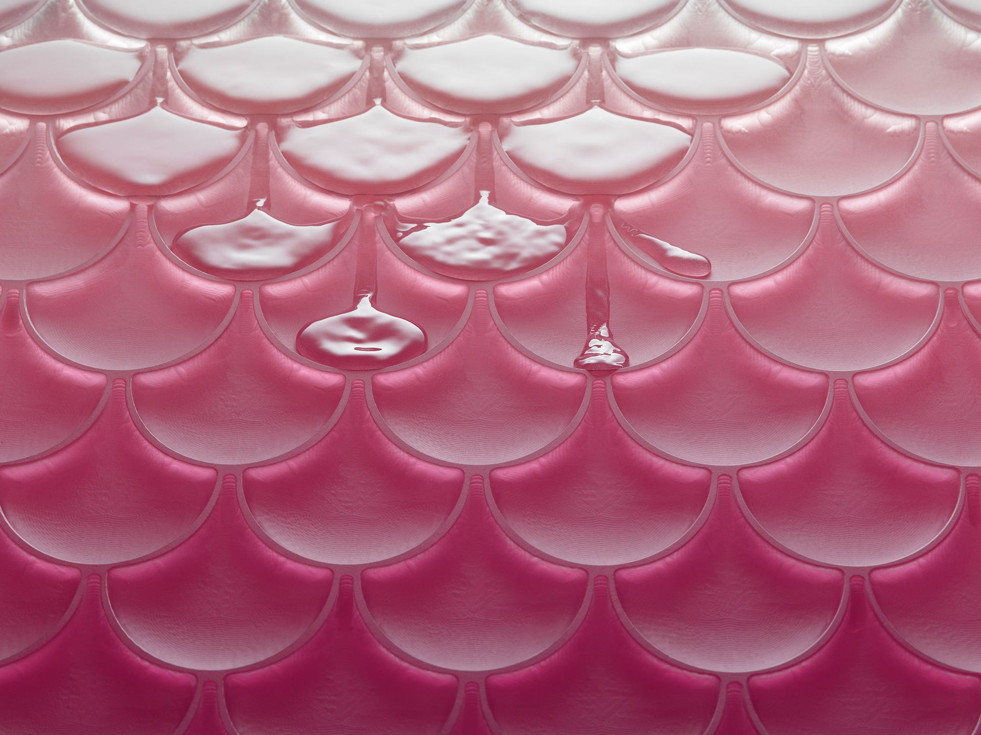 Tegels met roze en witte schubbenpatroon en waterdruppels, waardoor een gestructureerd oppervlak ontstaat.