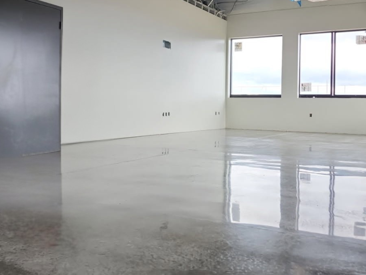 Garage with blue and gray speckled epoxy floor, white walls, and a closed door.