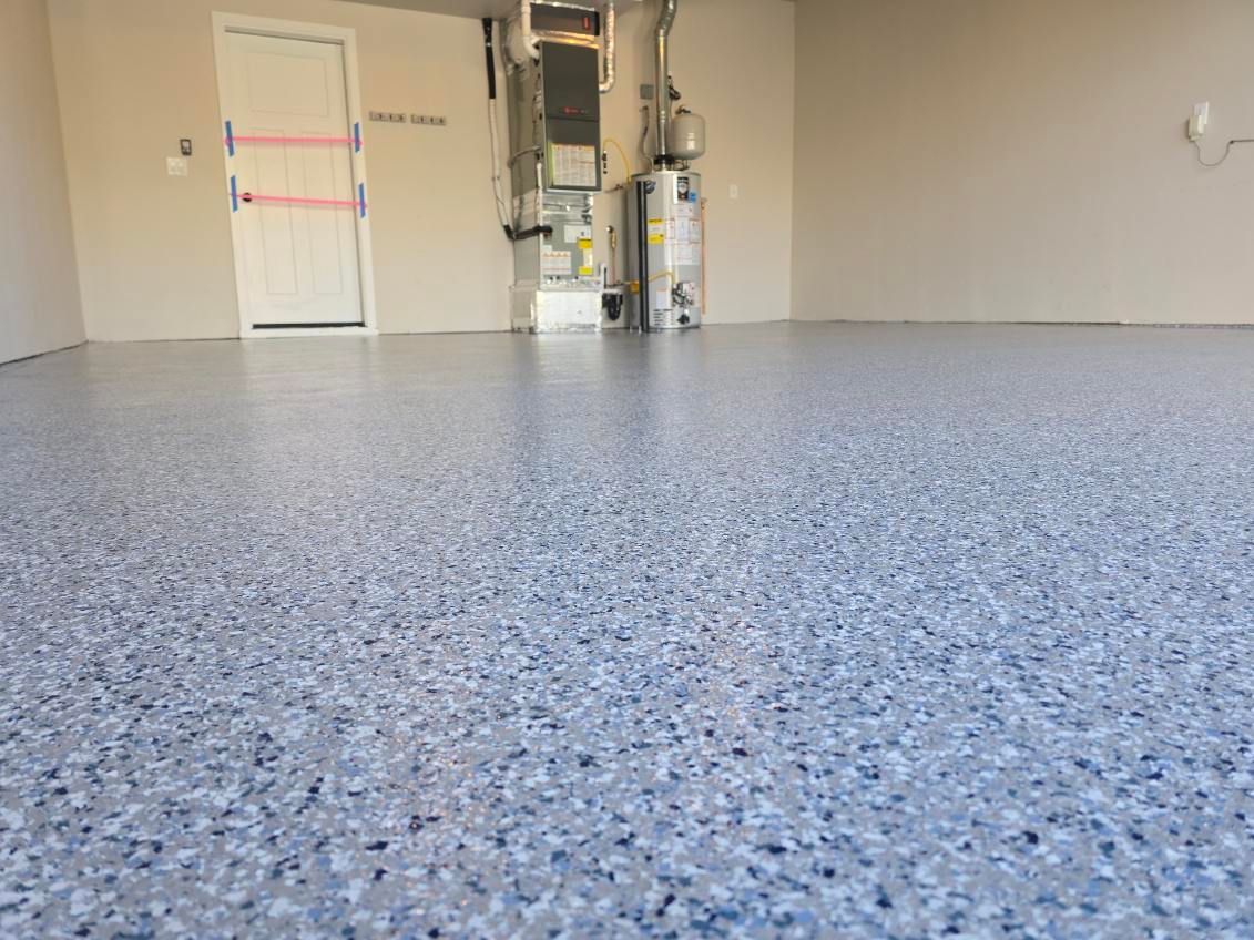 Garage with a blue and gray epoxy floor. A door, water heater, and HVAC are visible.