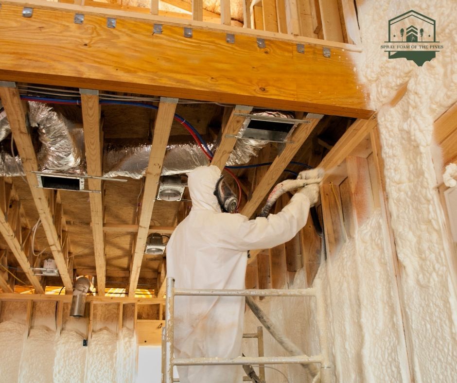 A man is spraying foam on a wall in a garage.