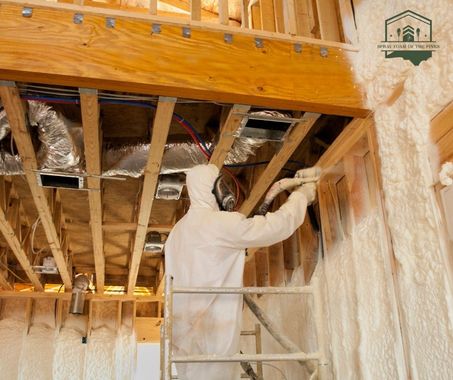 A man is spraying foam on a wall in a garage.