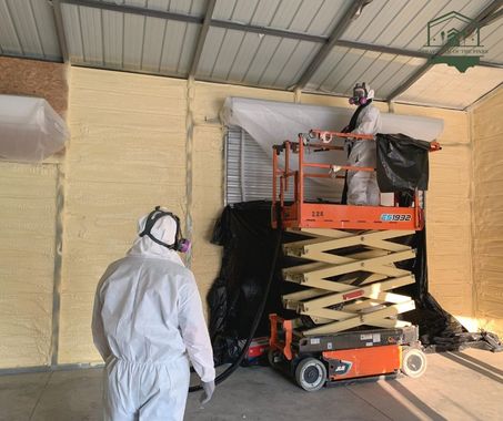 Two men in protective suits are working on a scissor lift.