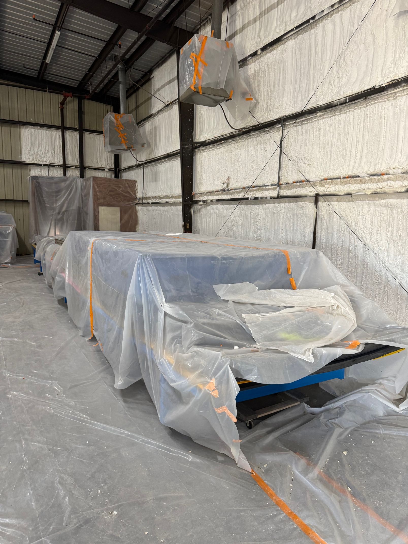 A man is spraying foam on a wall in a garage.