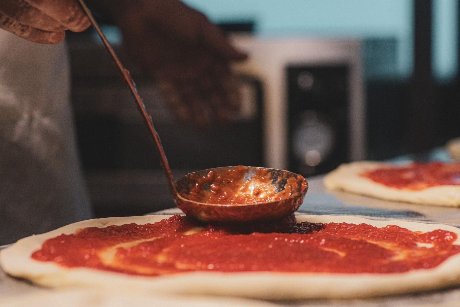 Una persona sta mettendo una pizza su un piatto su un tavolo di legno.