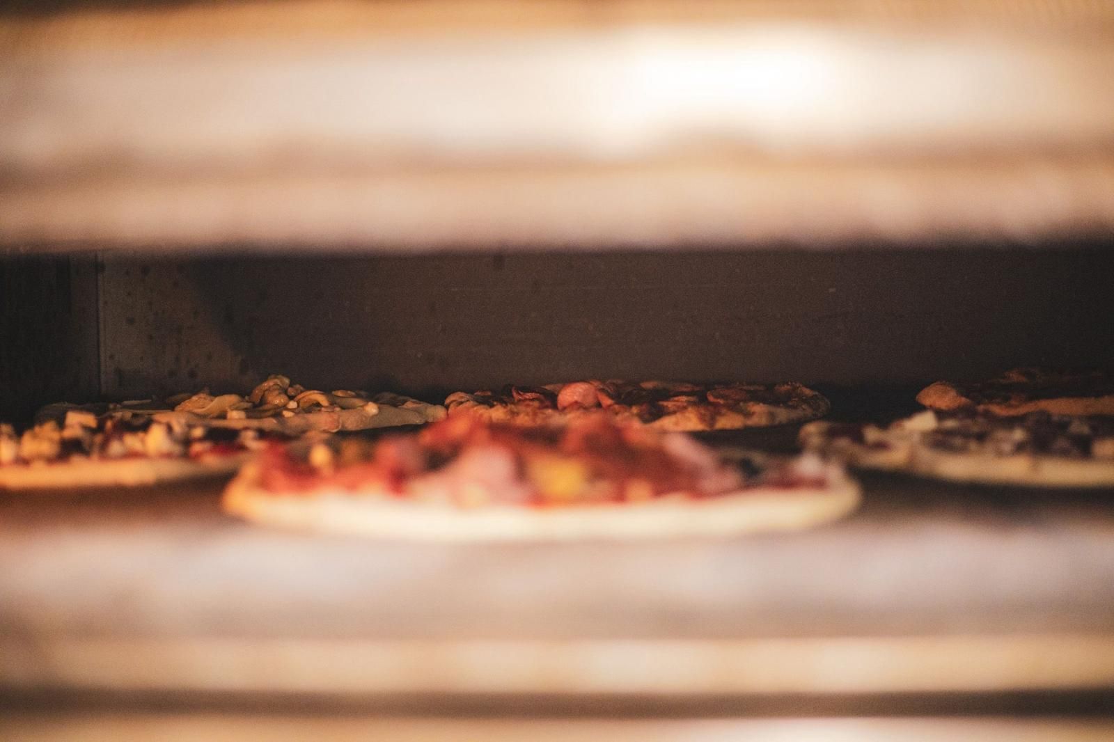 Una pizza viene tolta dal forno con una spatola.