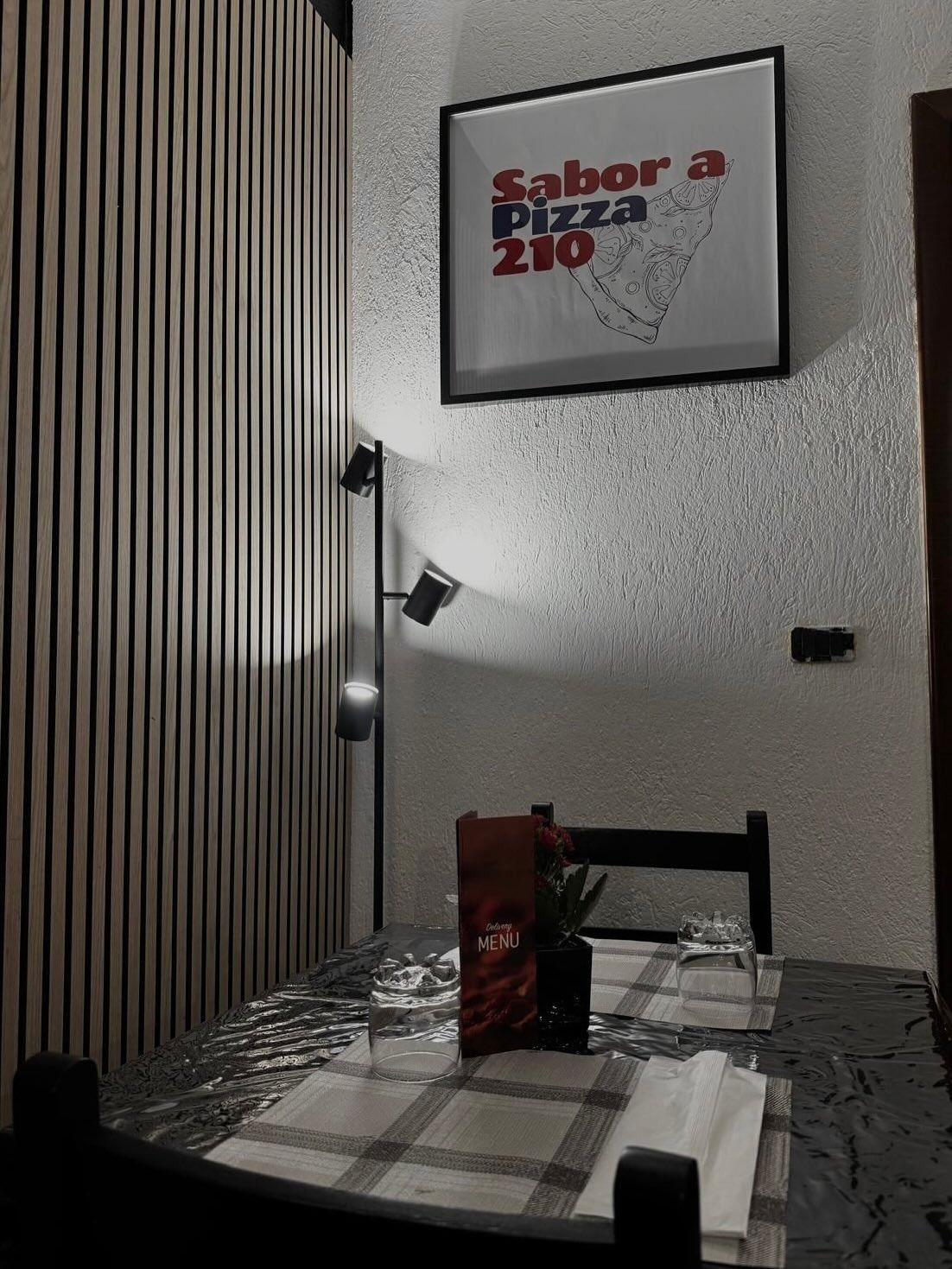 Un tavolo con un cartello sul muro che dice sabor a pizza 210