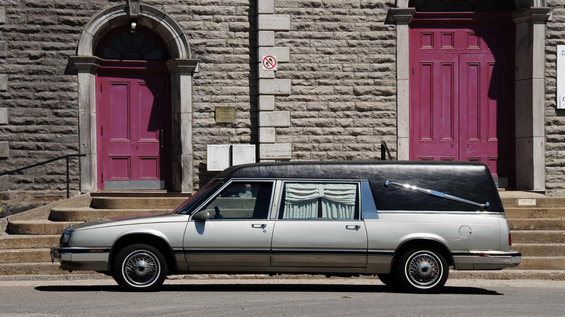 A man and a woman are sitting in the back seat of a limousine looking at a tablet.