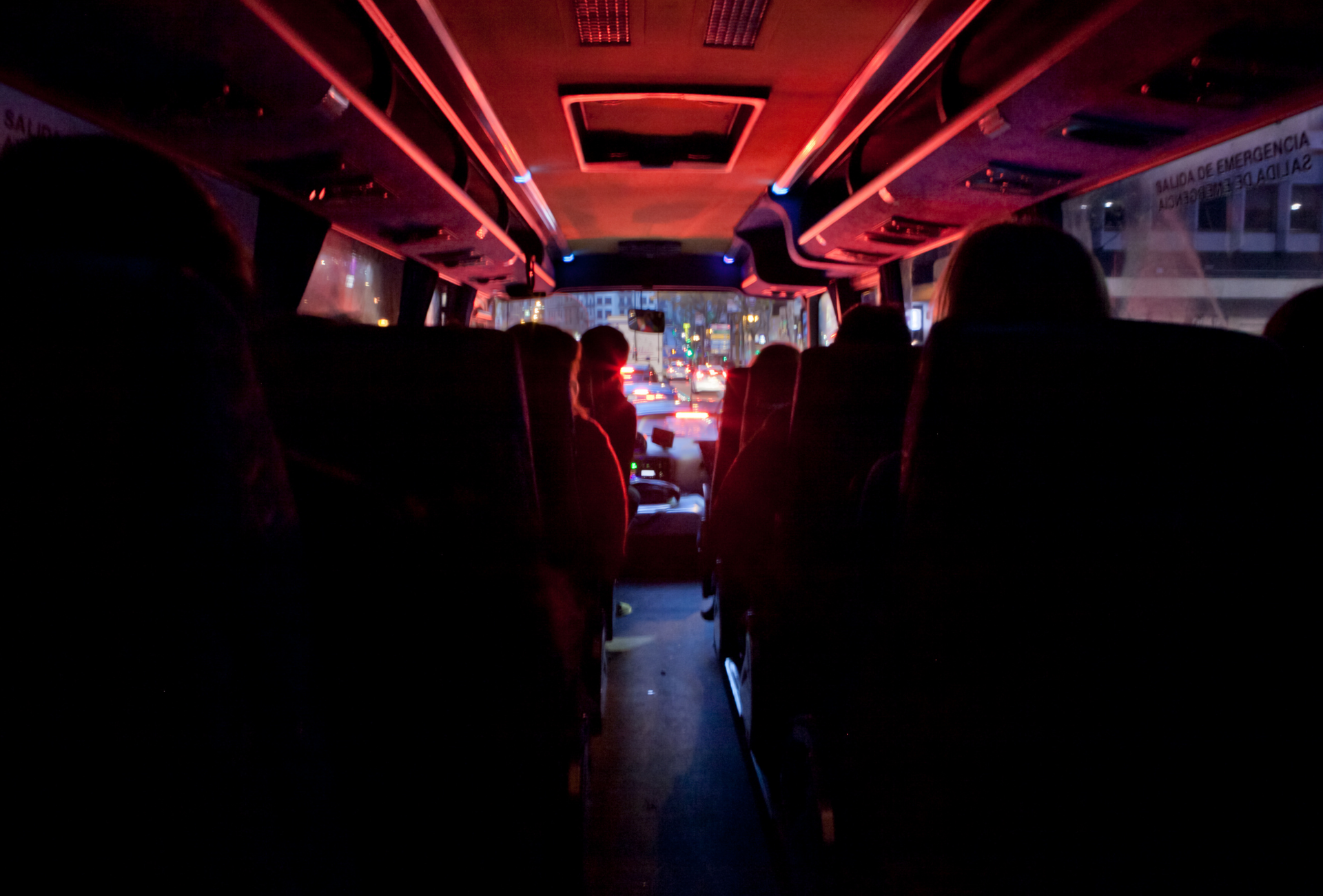 A group of people are sitting on a bus at night.