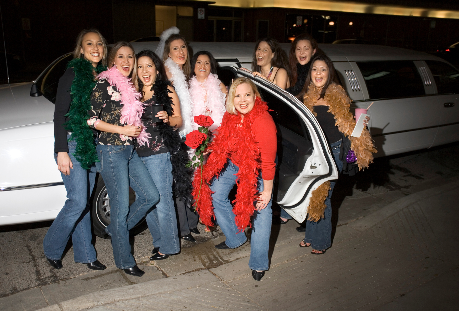 A group of women standing in front of a white limousine
