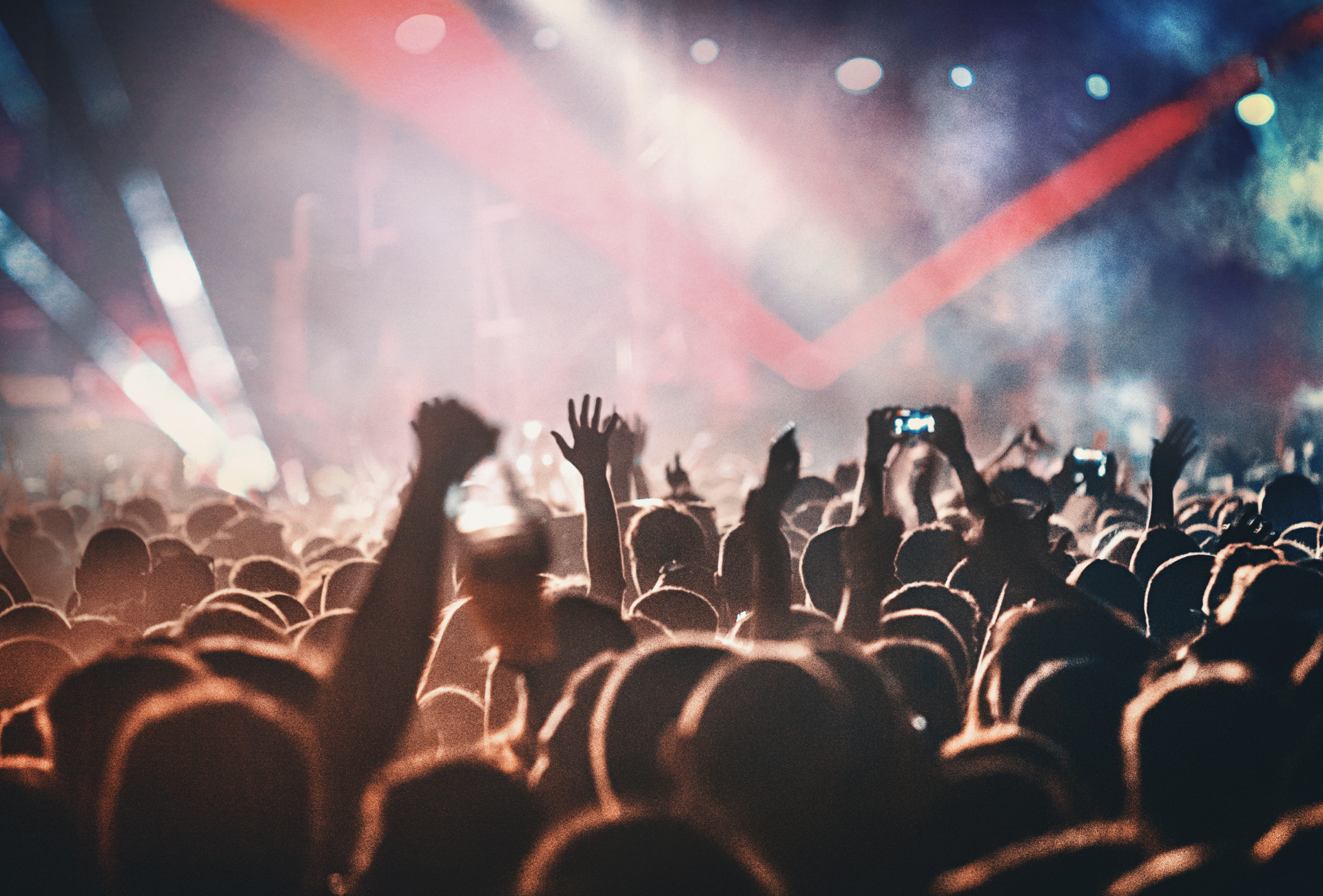 A crowd of people at a concert with their hands in the air.
