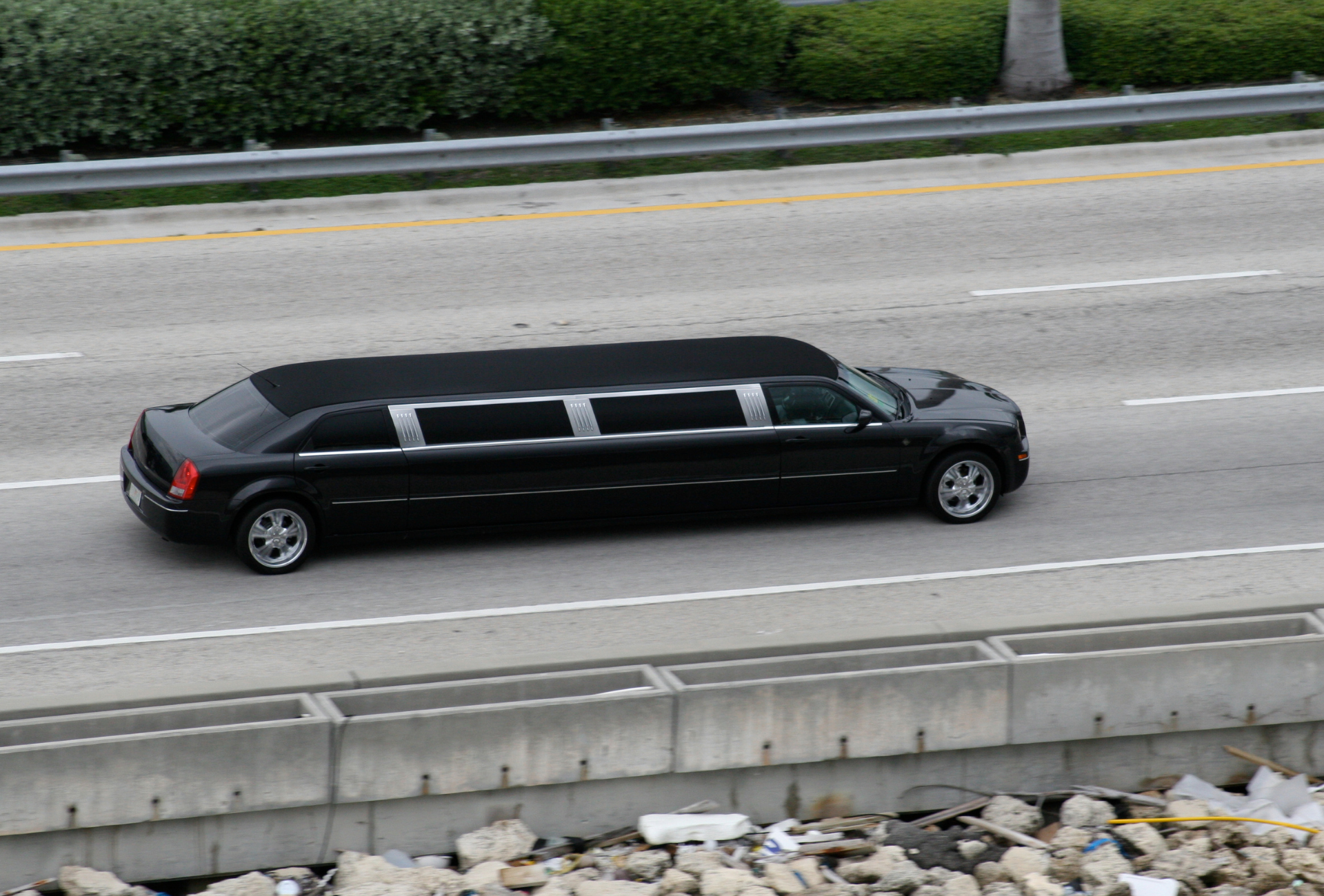 A black limousine is driving down a highway.