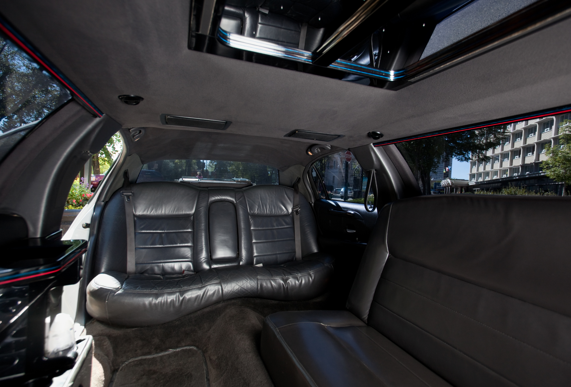 The back seat of a limousine with the sunroof open.