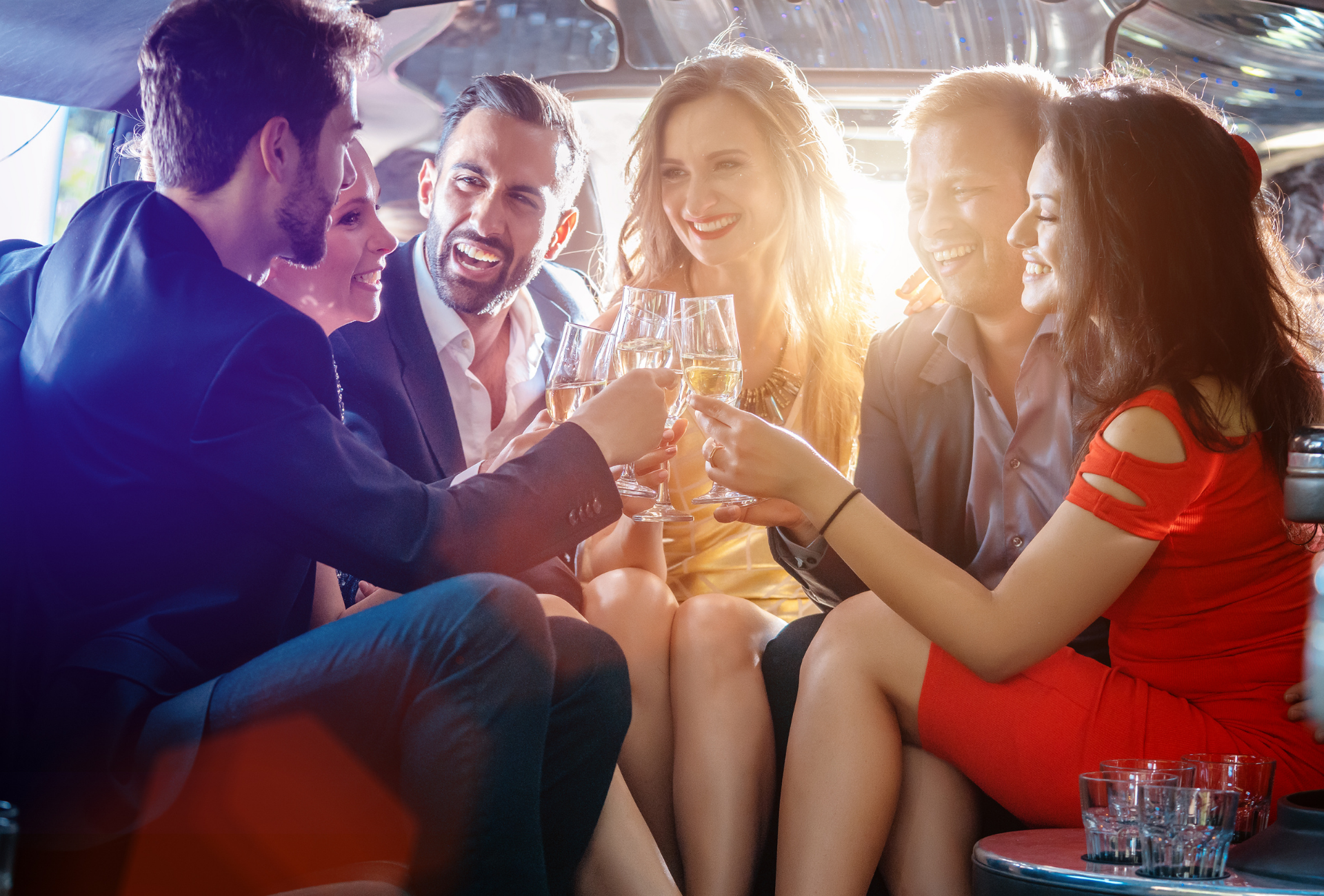 A group of people are sitting in a limousine toasting with champagne glasses.
