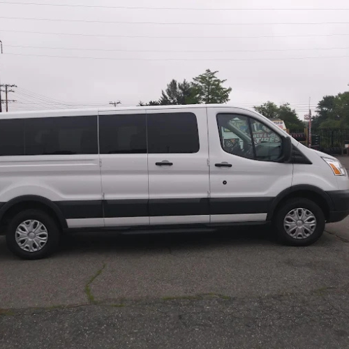 A group of women in dresses are walking towards a bus.