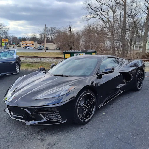 A man is waving from the back of a limousine in front of a private jet.