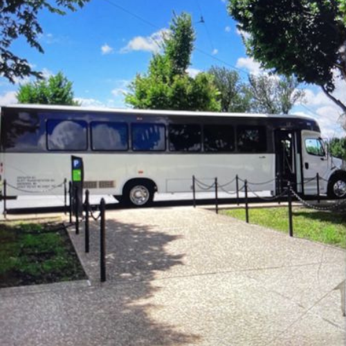 A man in a suit and tie is sitting in a car talking on a cell phone.