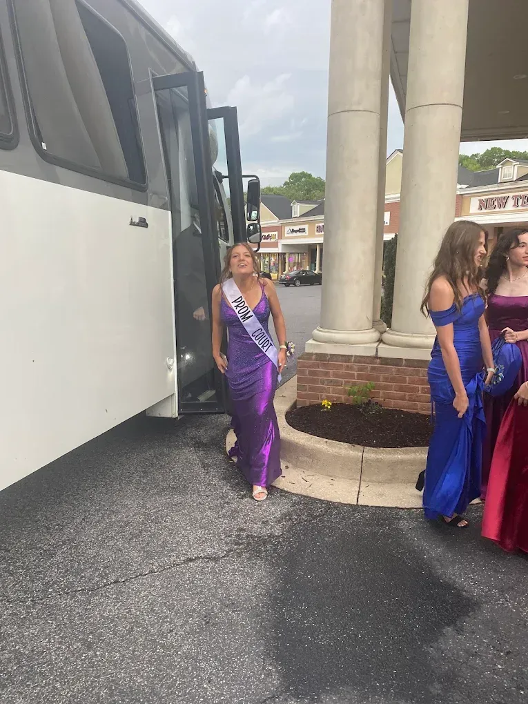 A group of women in dresses are walking towards a bus.