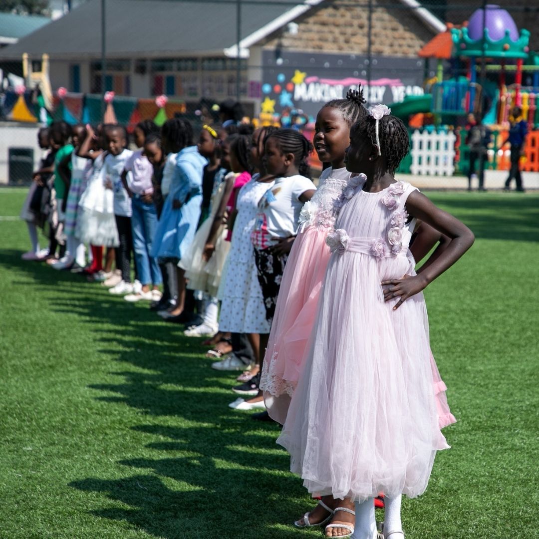 A group of young girls in pink dresses are standing in a line