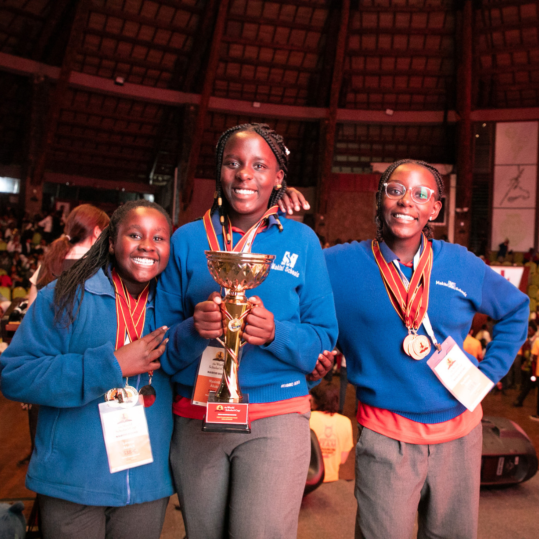 Three girls in blue sweaters holding a trophy