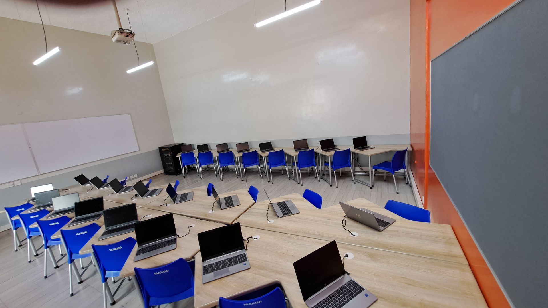 A classroom with a lot of laptops on tables and chairs
