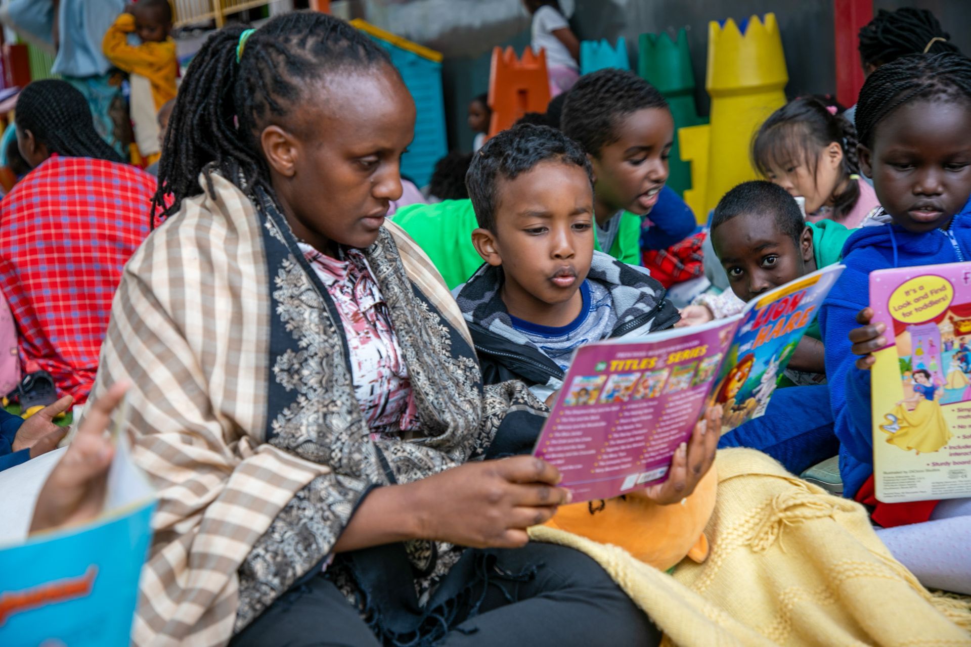 A woman is reading a book to a group of children.
