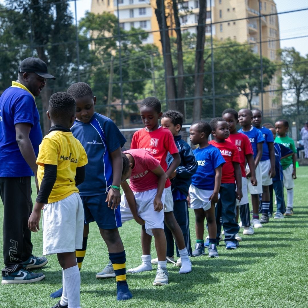 A group of children are standing in a line on a soccer field
