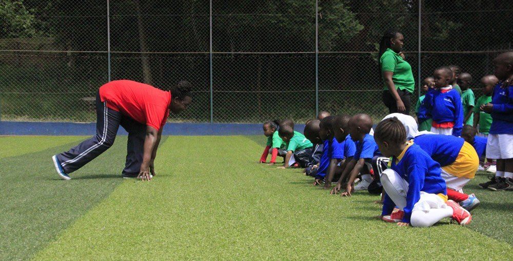 A group of children are kneeling on the grass on a field.