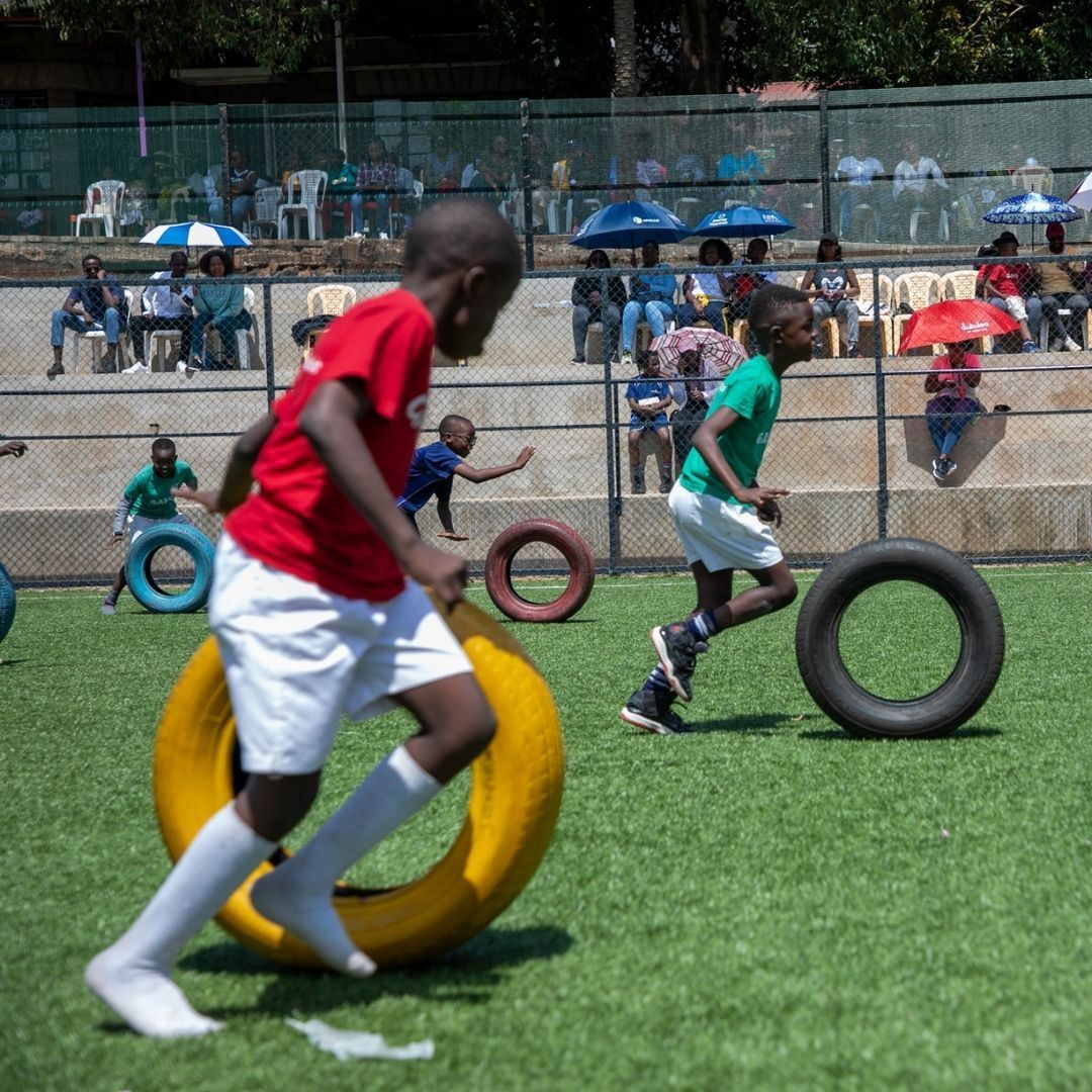 A group of children are playing with tires on a field.