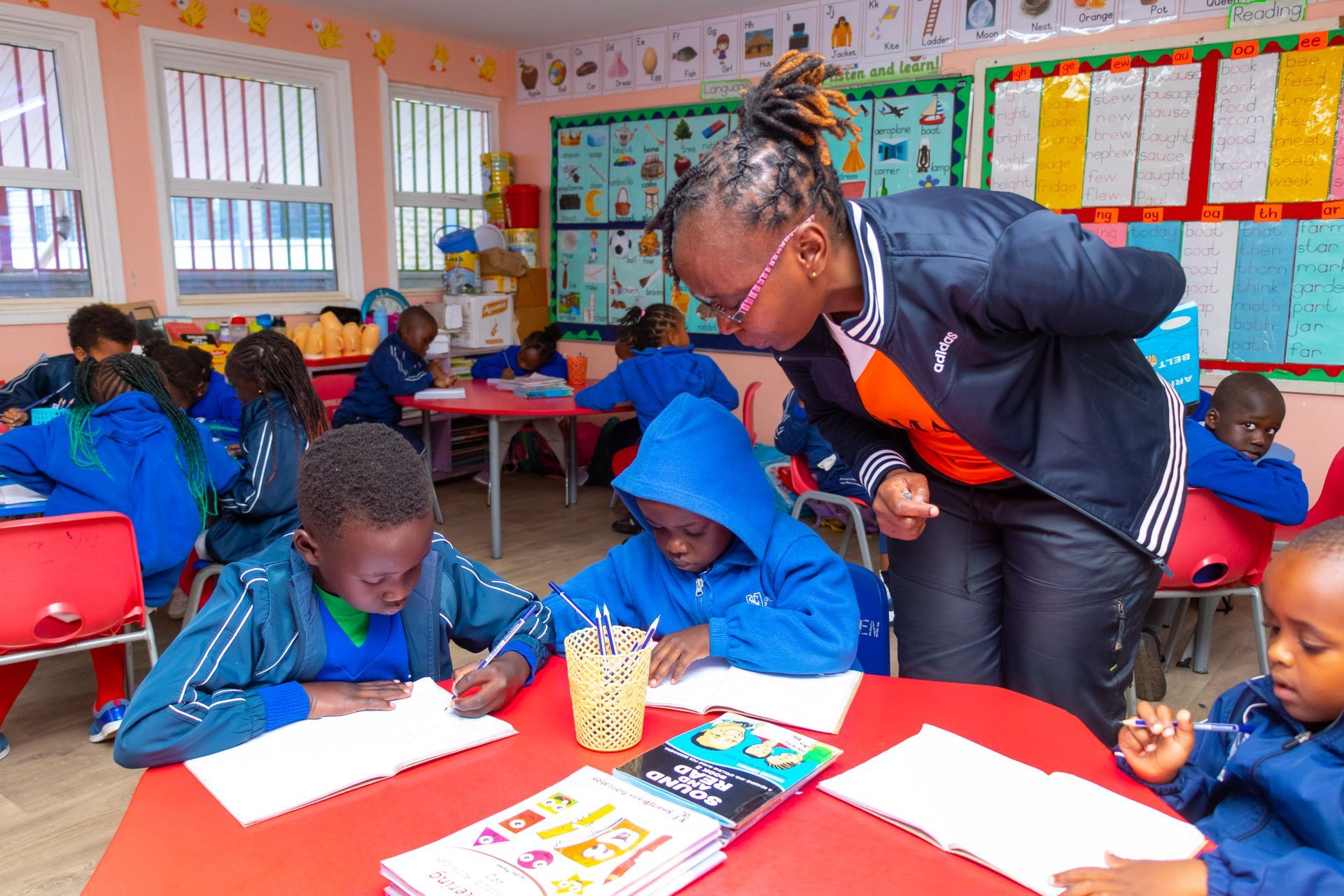A woman is teaching a group of children in a classroom.
