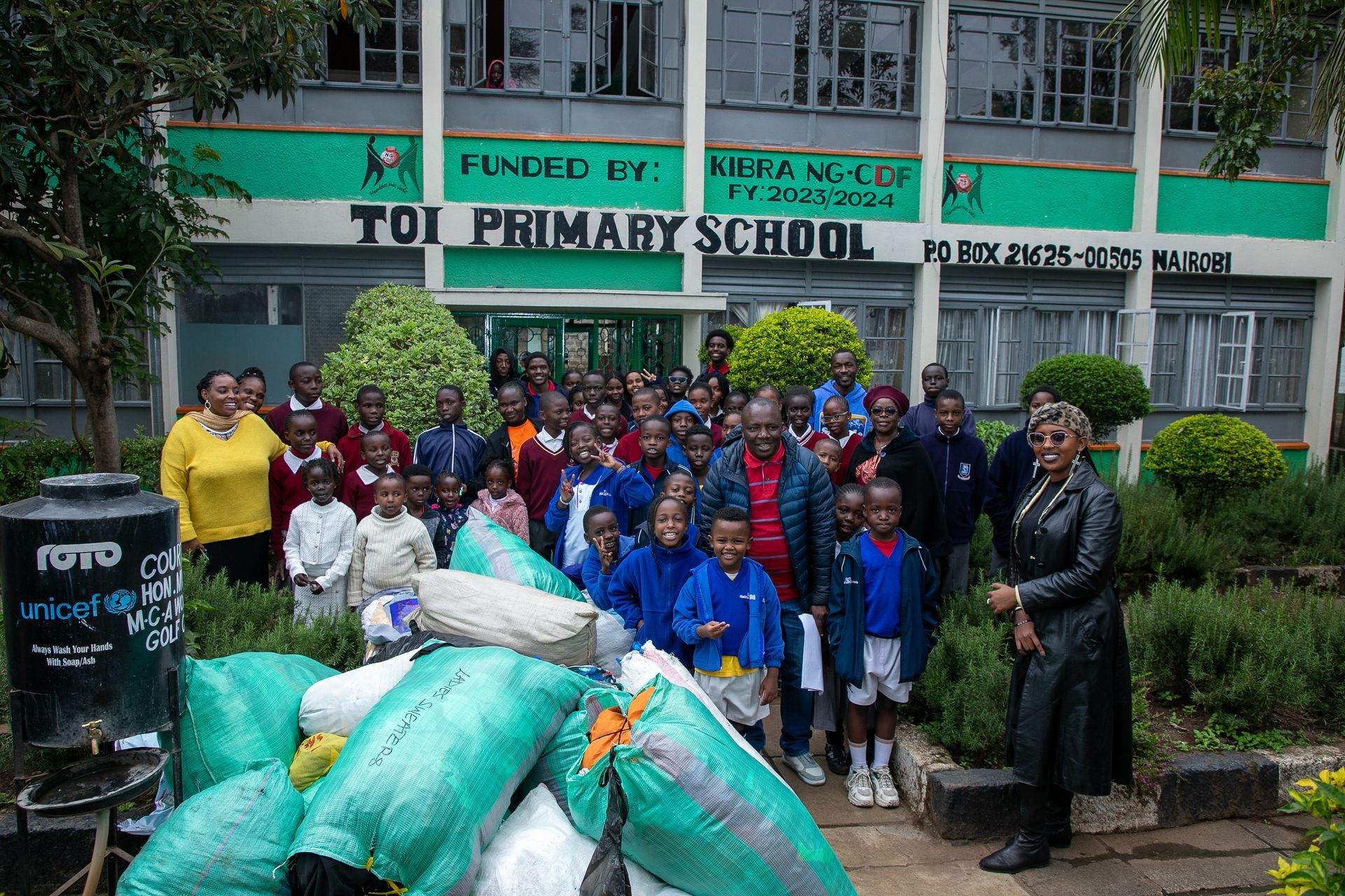 A group of people standing in front of a toi primary school