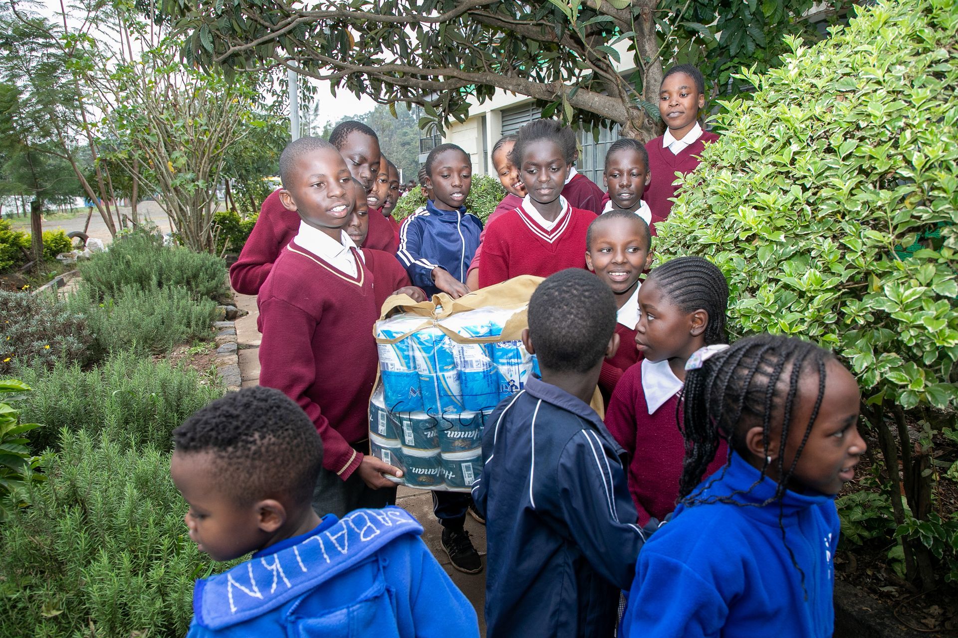 A group of children are carrying a pallet of water