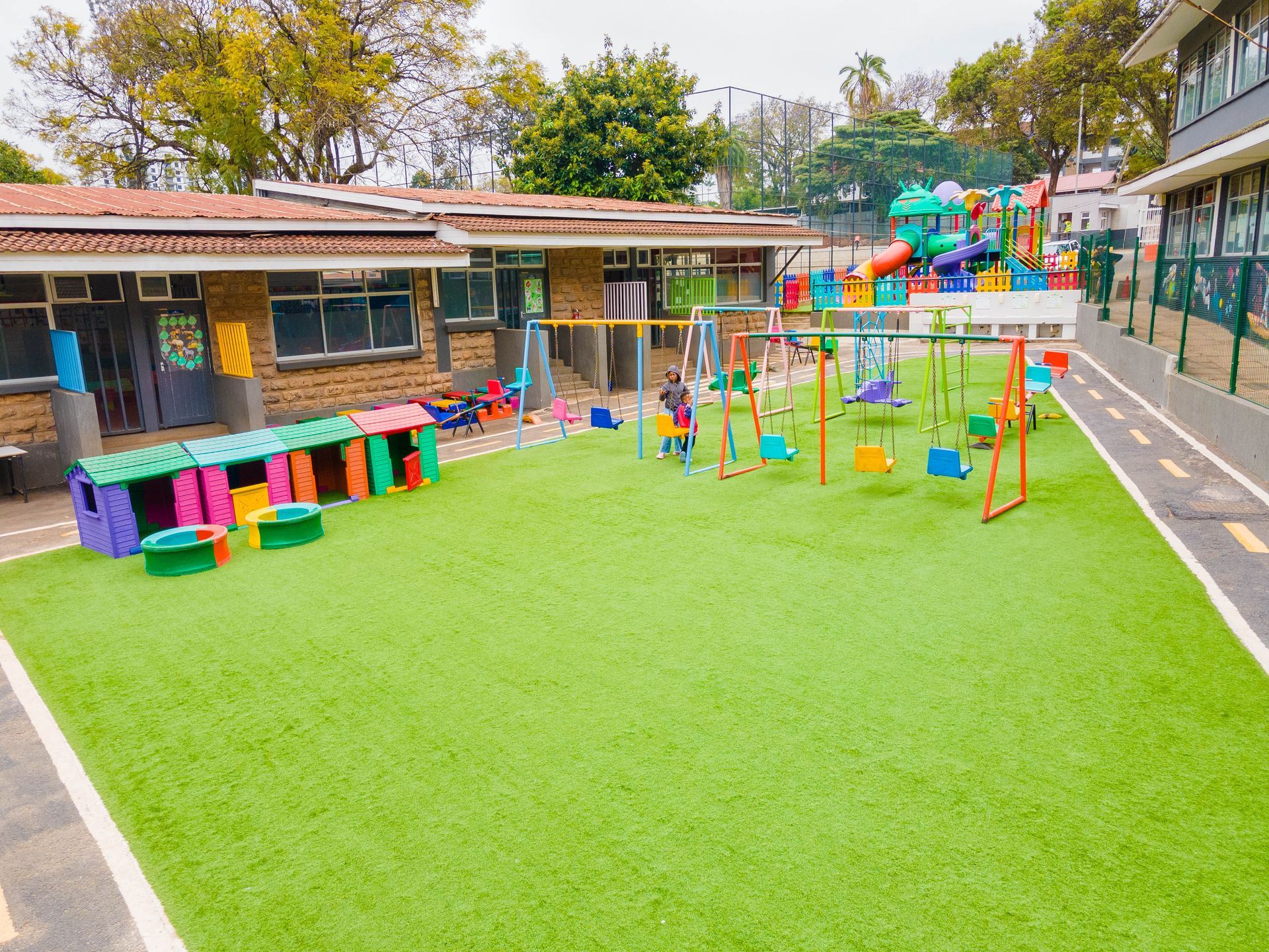 A playground with a lot of colorful toys on it in front of a building.