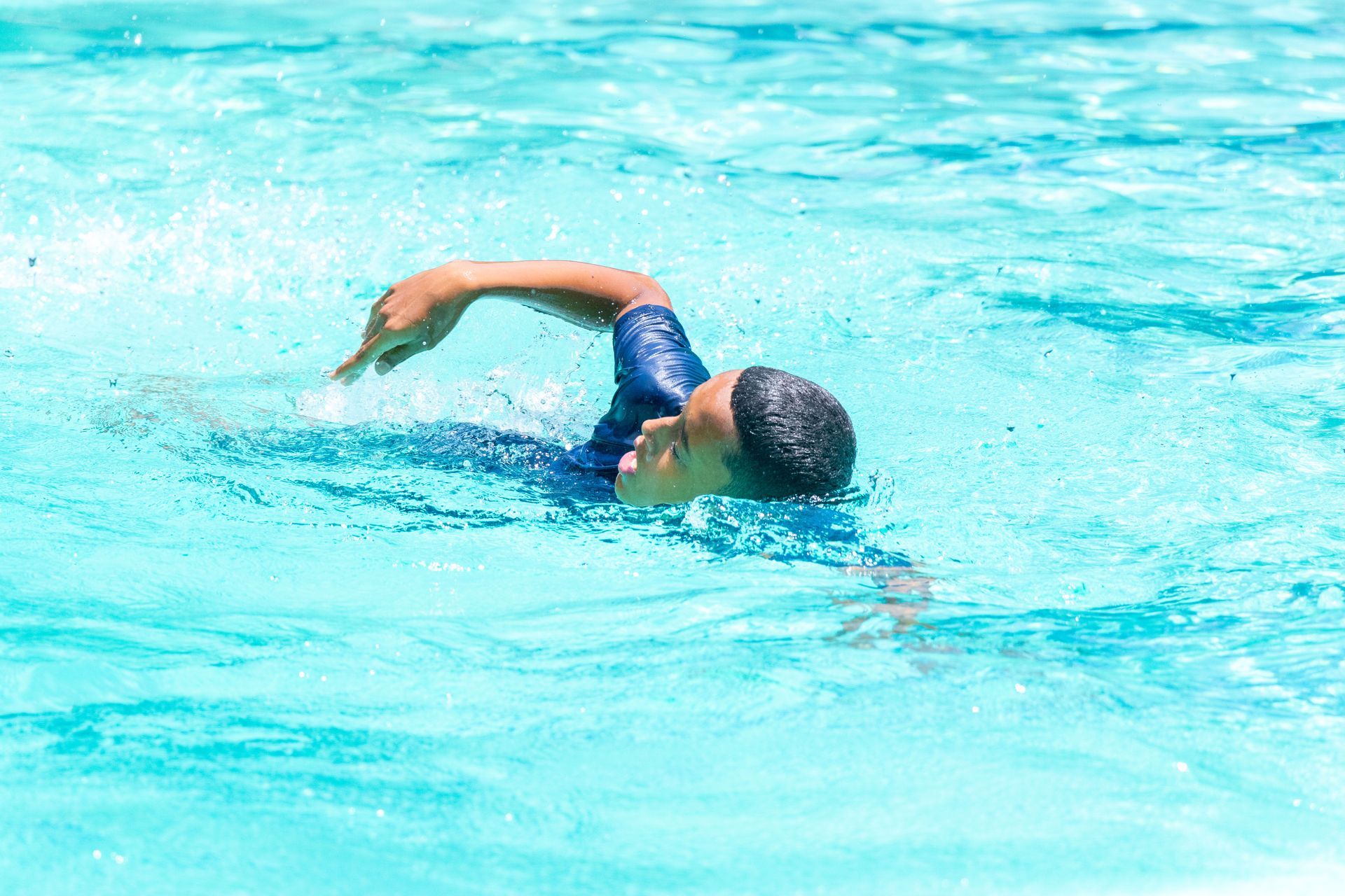 A young boy is swimming in a swimming pool.