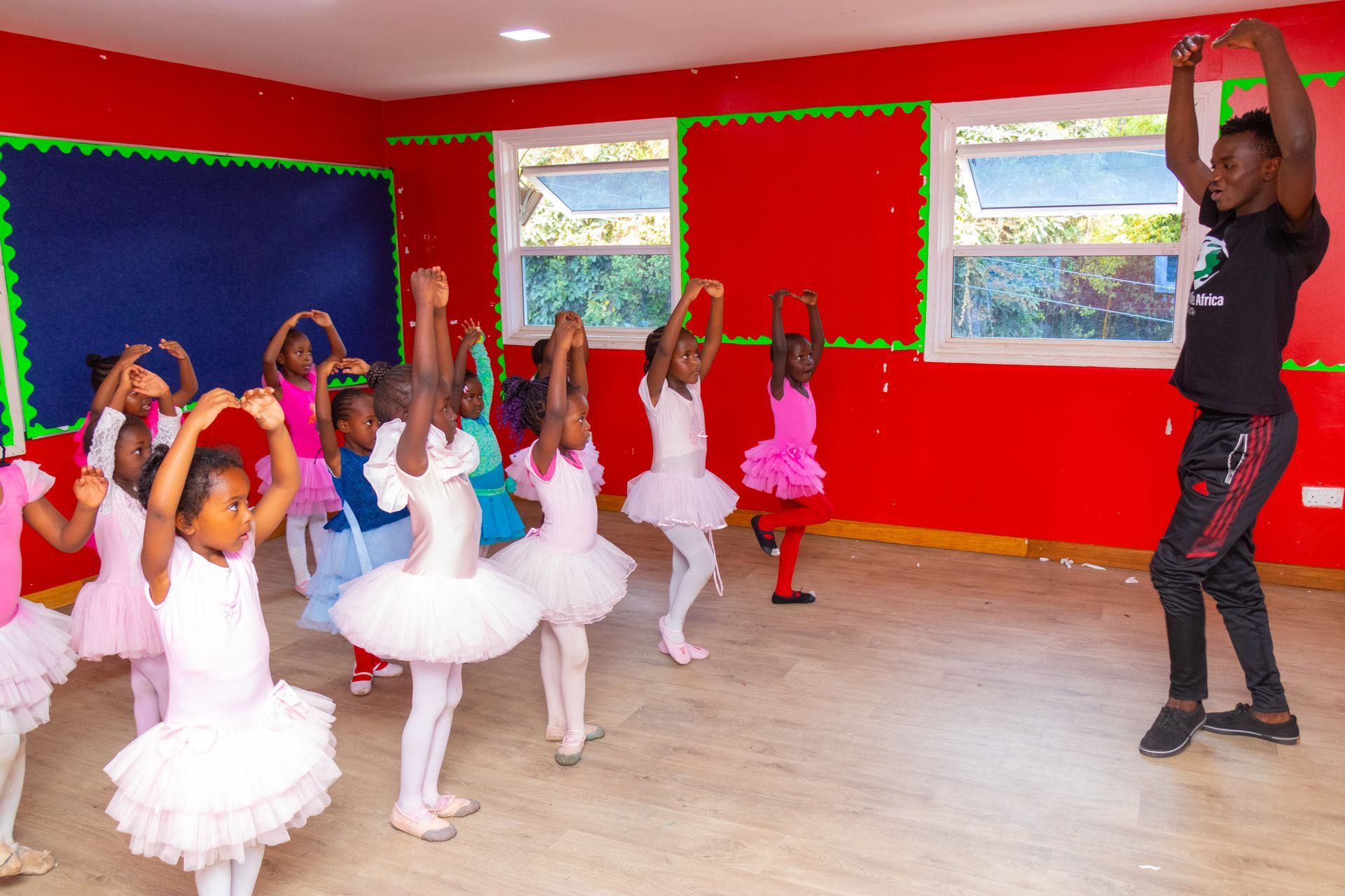 A group of young girls in tutus are dancing in a dance studio.