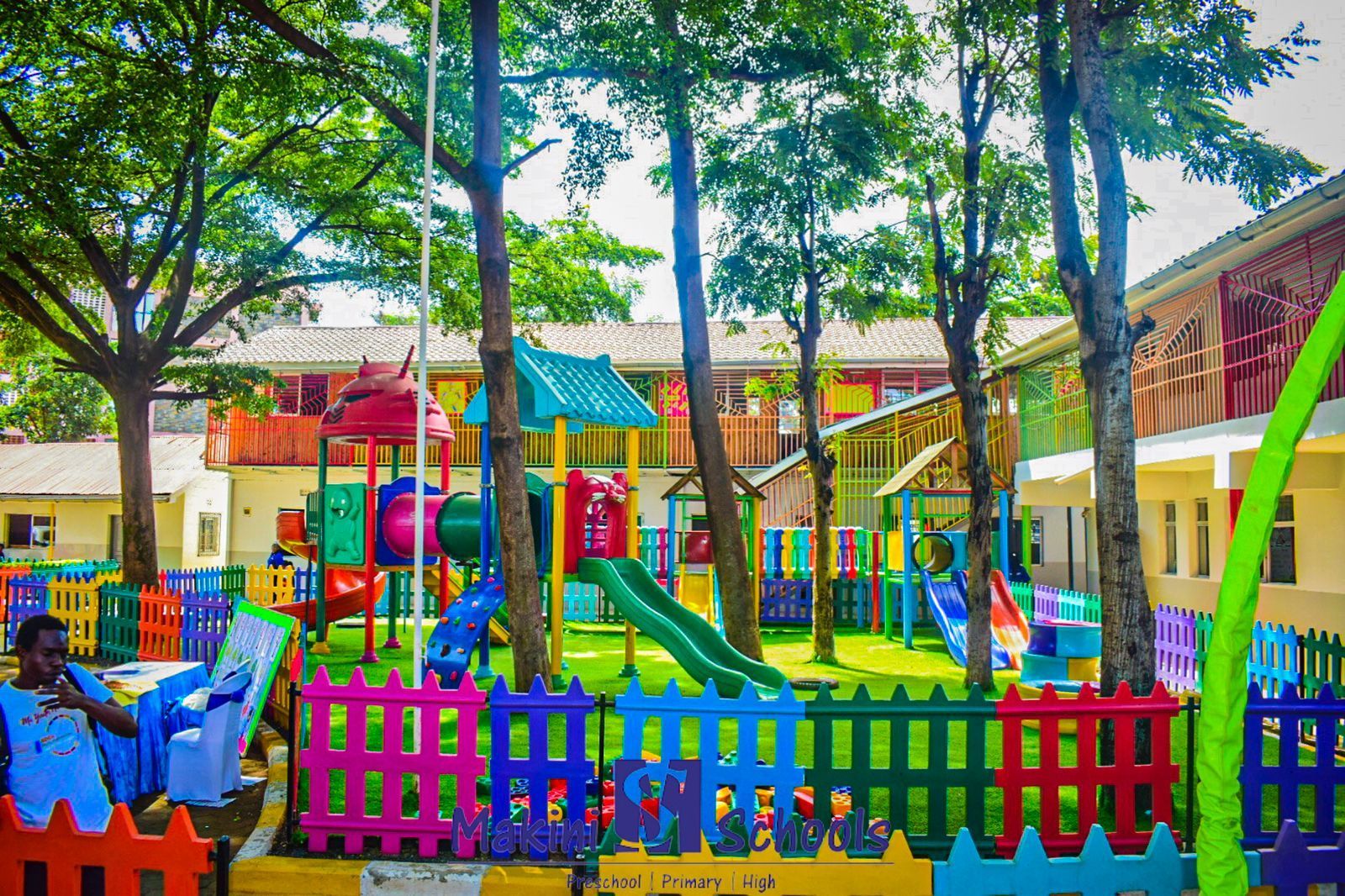 A man is sitting in a chair in front of a colorful playground.