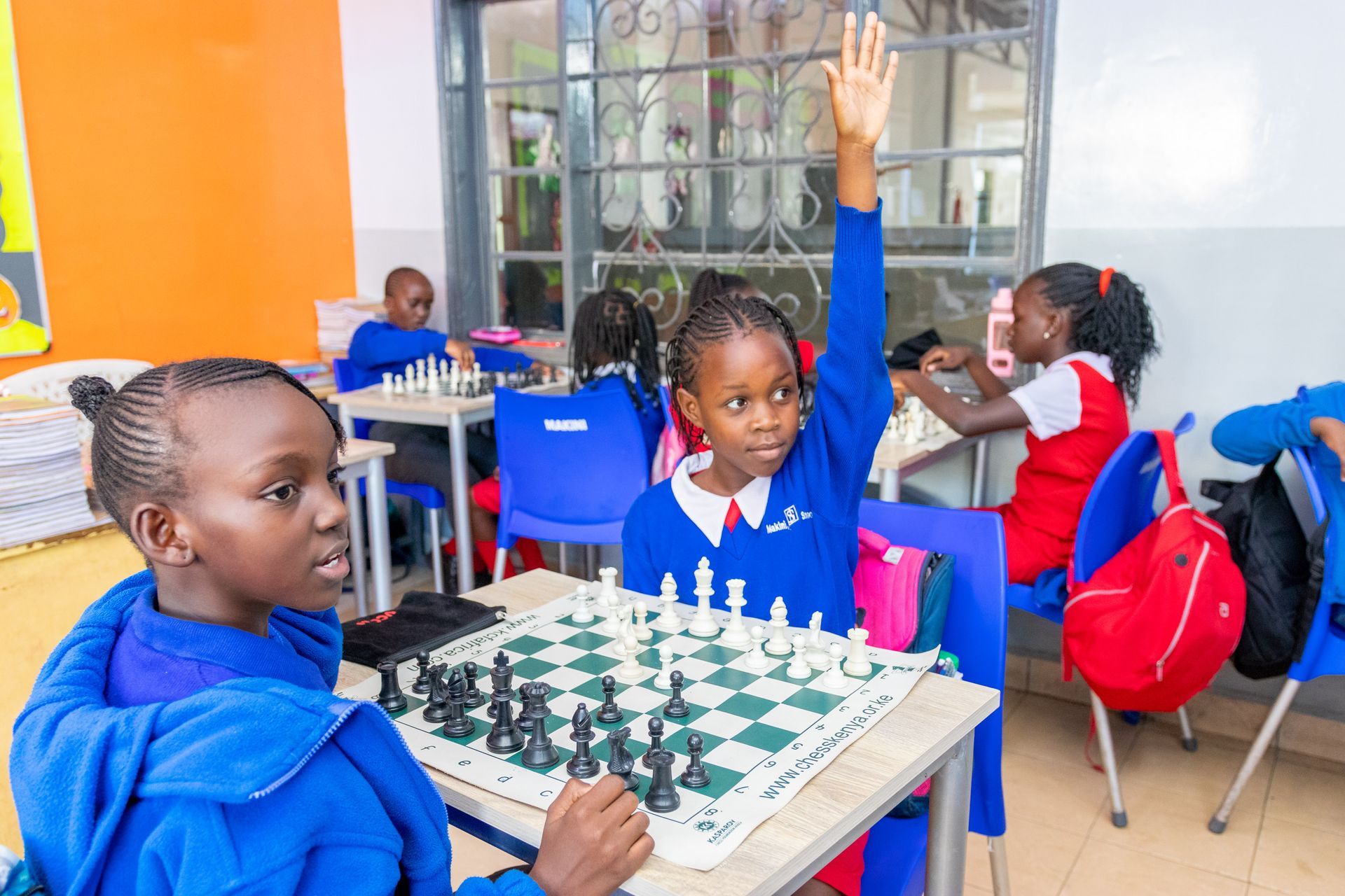 A group of children are playing chess in a classroom.
