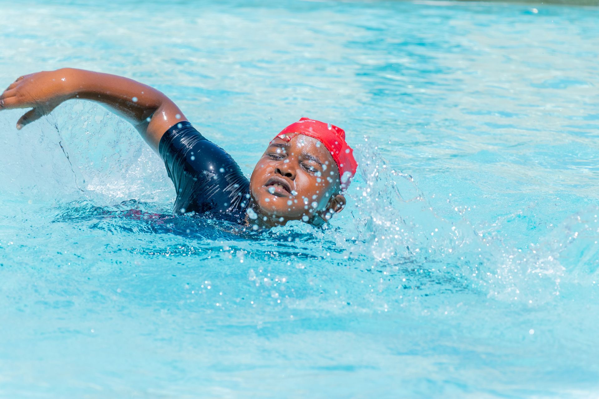 A young boy is swimming in a swimming pool.
