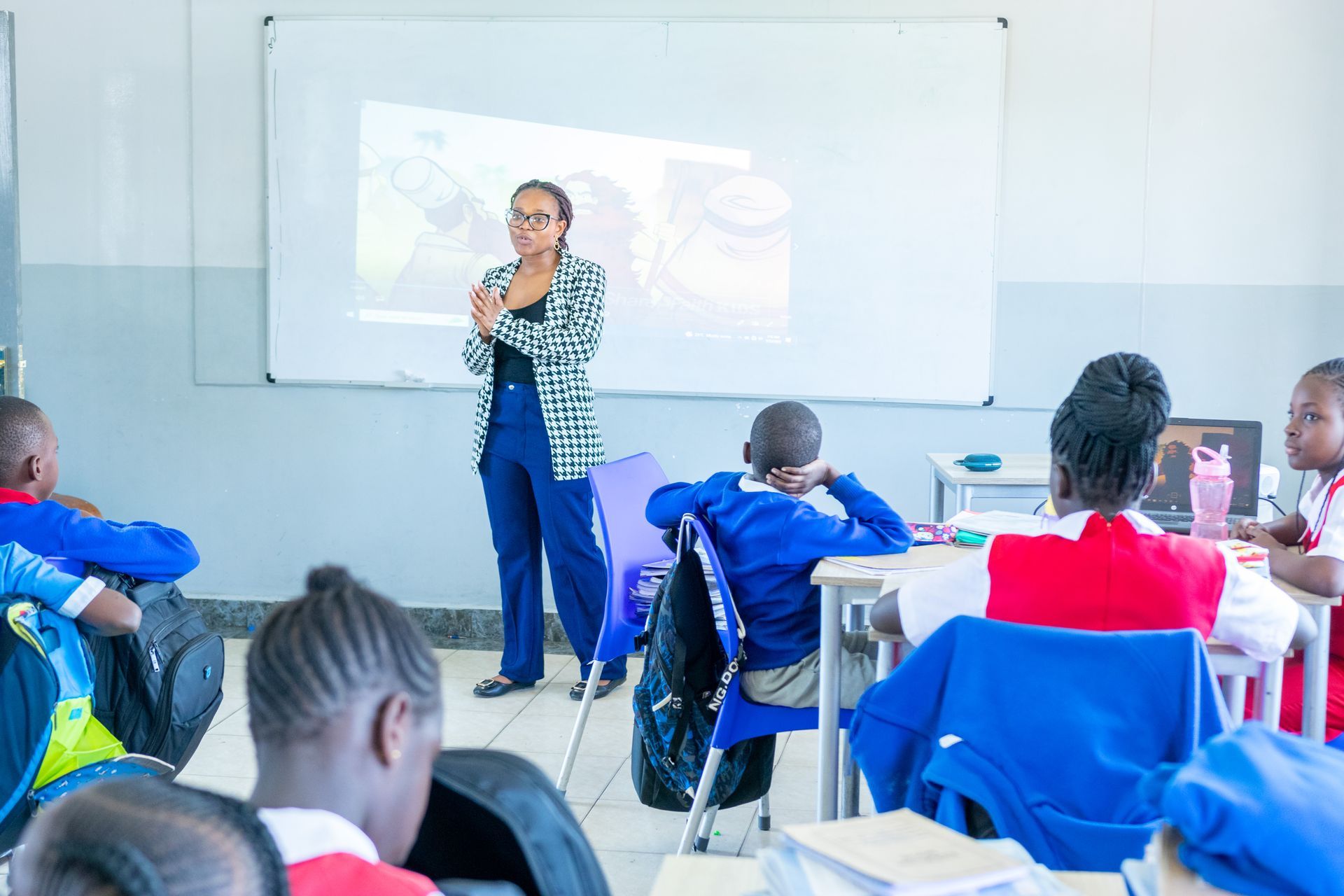 A teacher is giving a presentation to a group of students in a classroom.