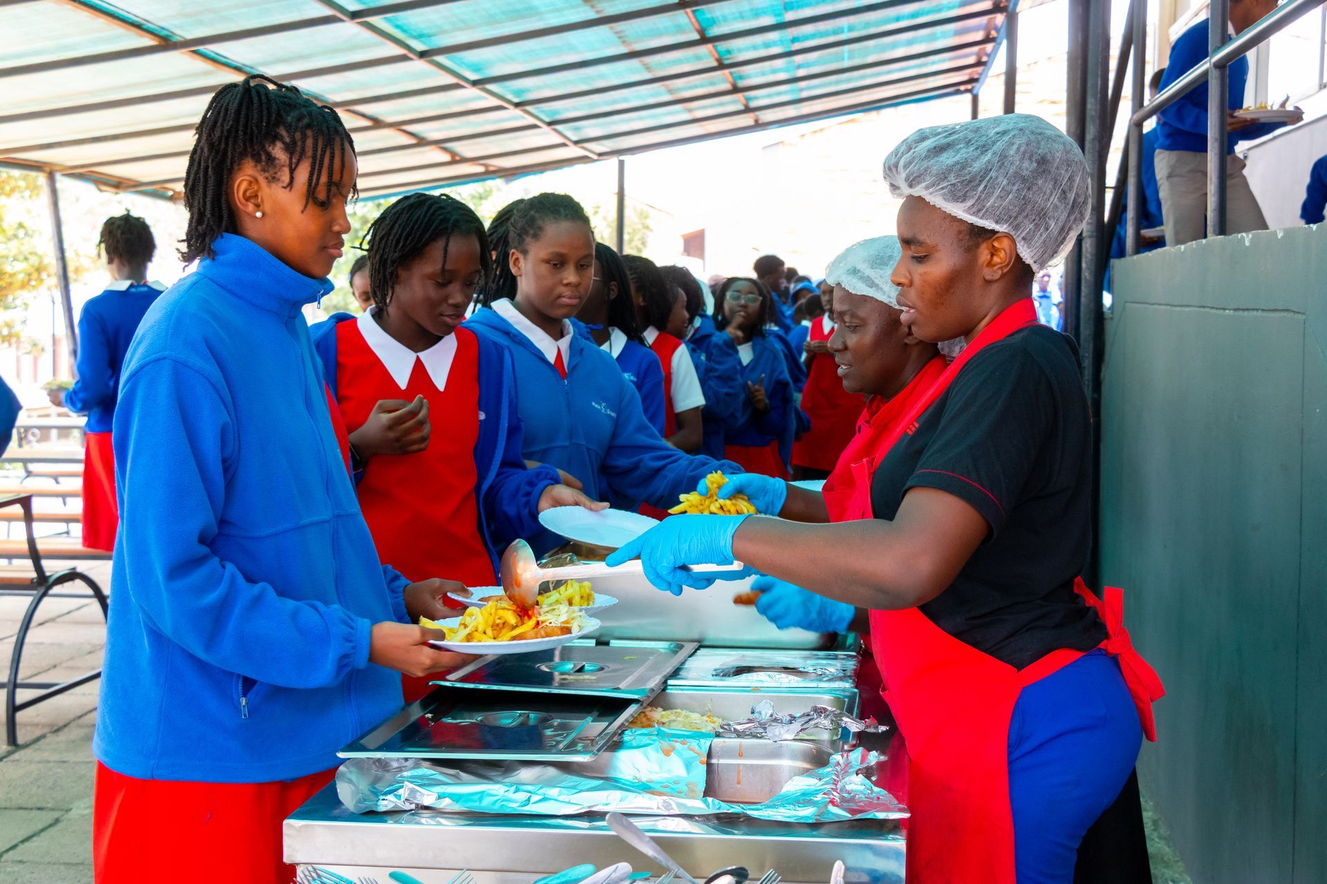 A woman is serving food to a group of children.
