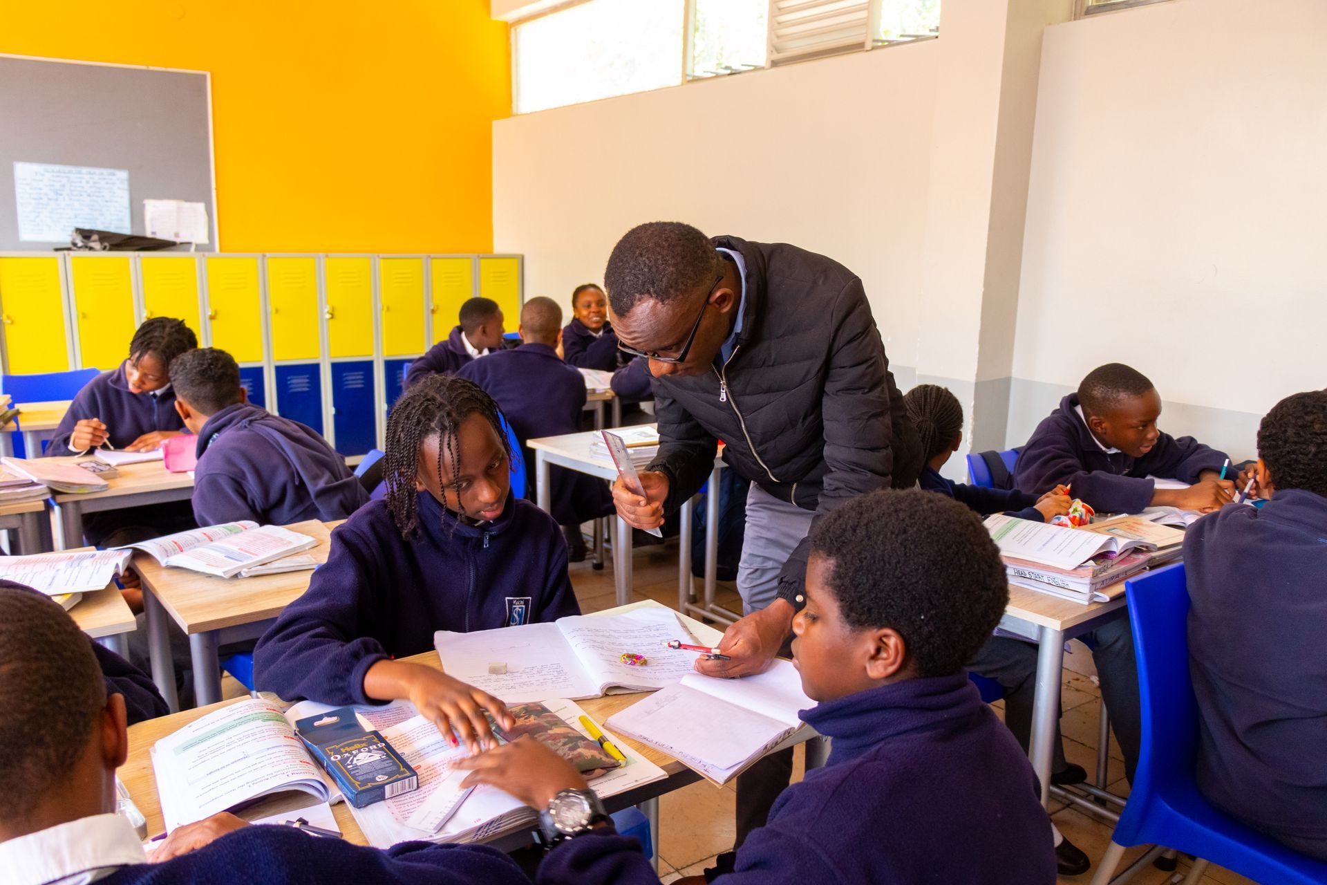 A teacher is helping a group of students in a classroom.