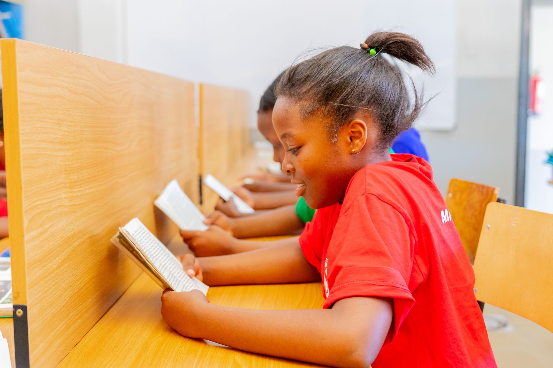 A group of children are sitting at a table reading books.