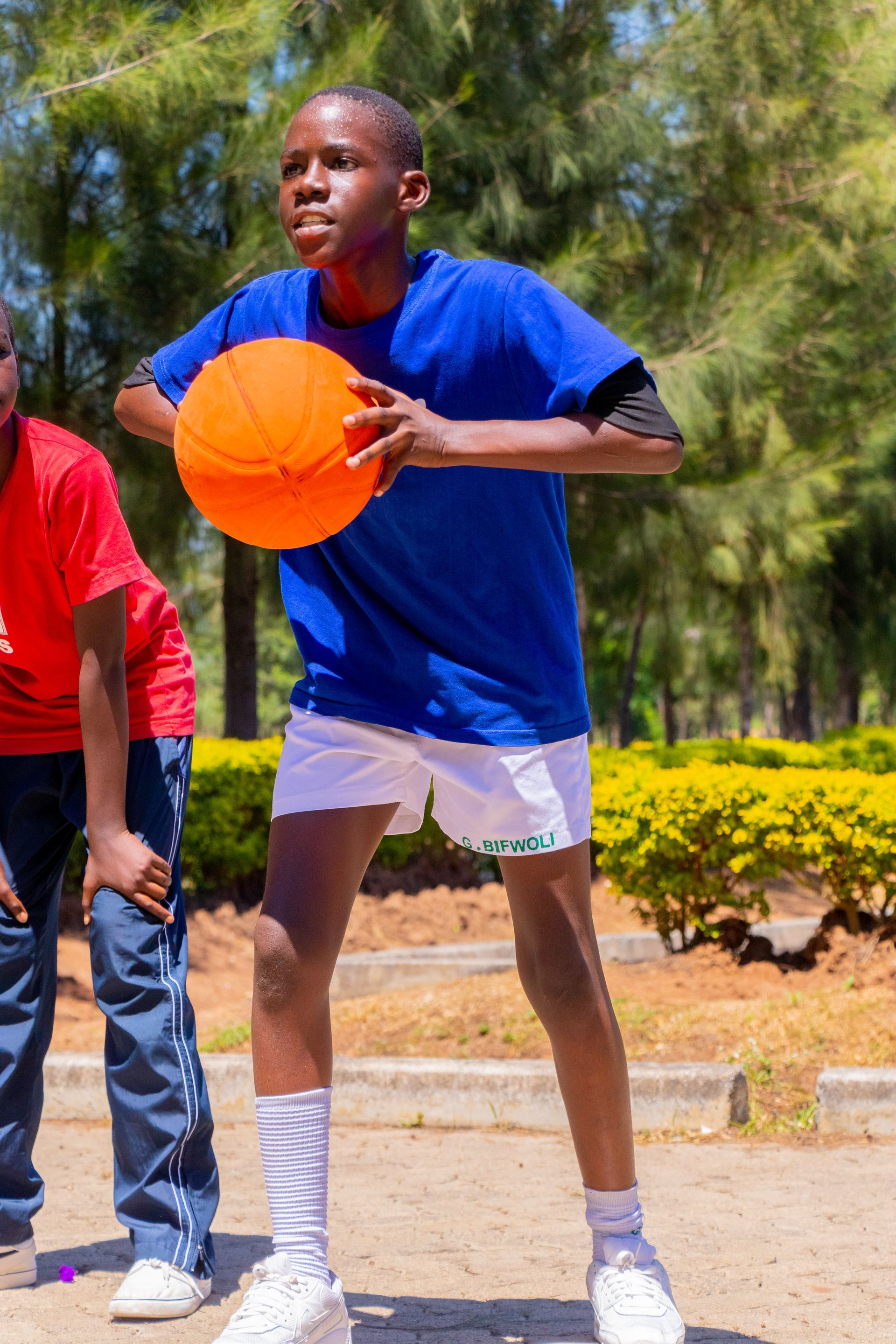 A young boy in a blue shirt is holding an orange basketball.