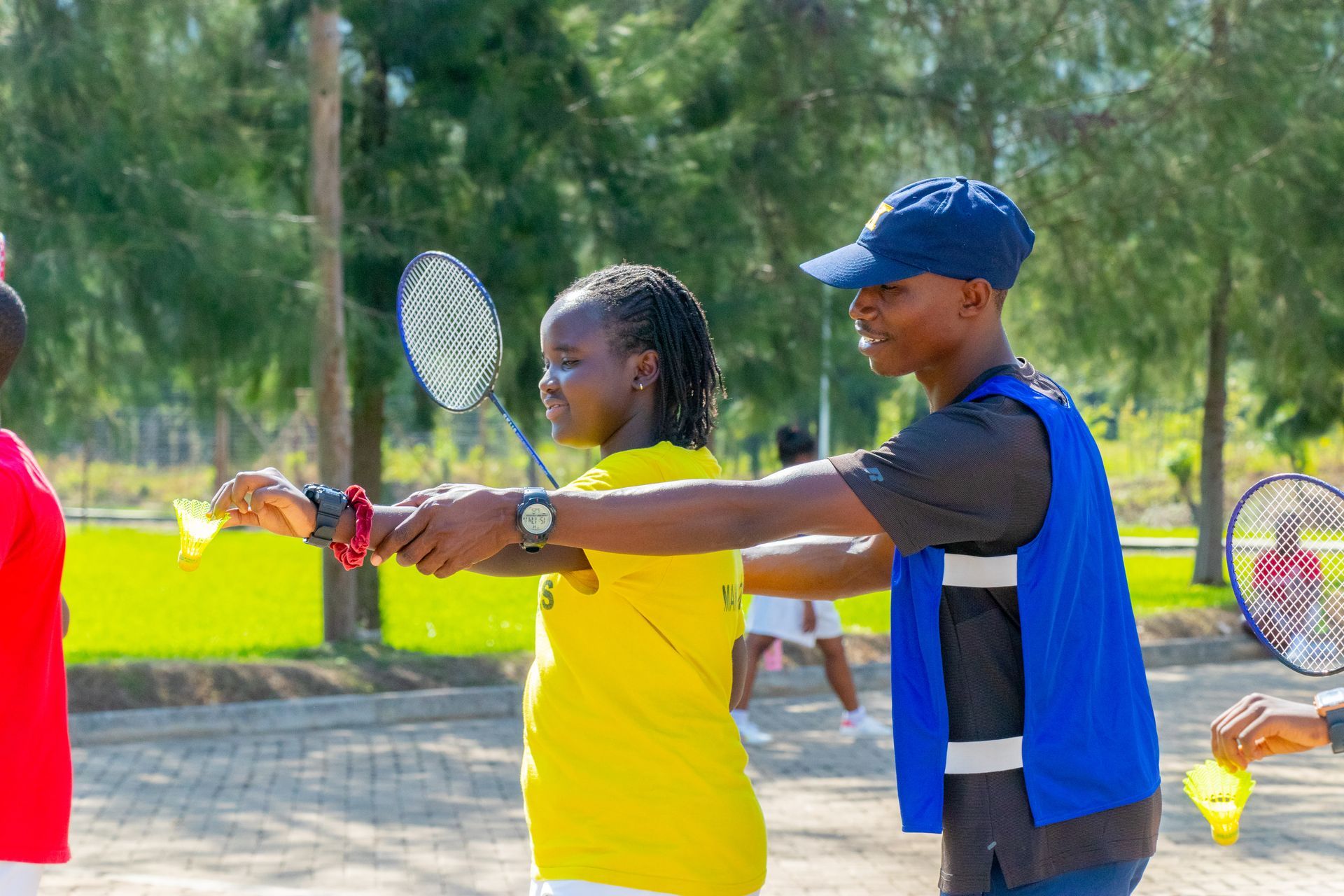 A man is teaching a girl how to play badminton.